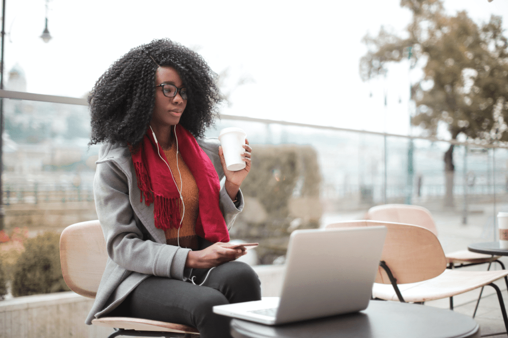 Frau am Laptop mit Kaffee in der Hand